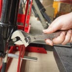 Using a Tolsen 10-inch adjustable wrench to tighten a bolt on machinery