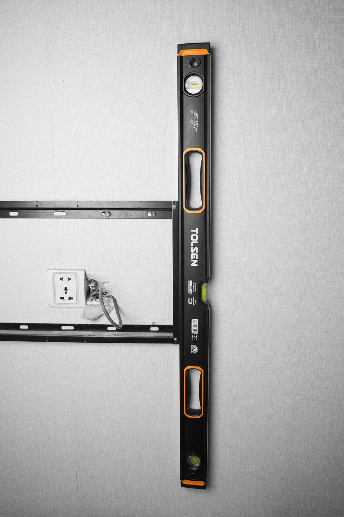 TOLSEN spirit level attached vertically to a metal wall bracket, demonstrating its strong magnetic base in use.