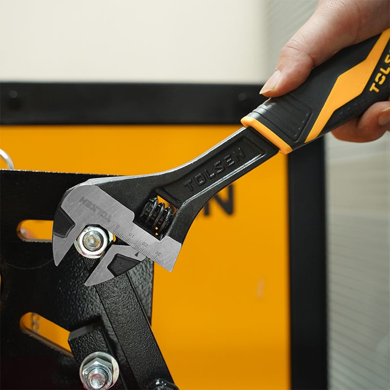 Close-up of a hand using a Tolsen 12 inch adjustable wrench to turn a bolt