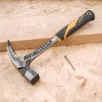 Tolsen one-piece forged roofing hammer and two nails on a wooden board
