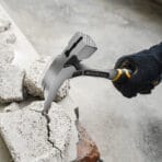 Tolsen one-piece forged roofing hammer being used to break apart concrete or masonry