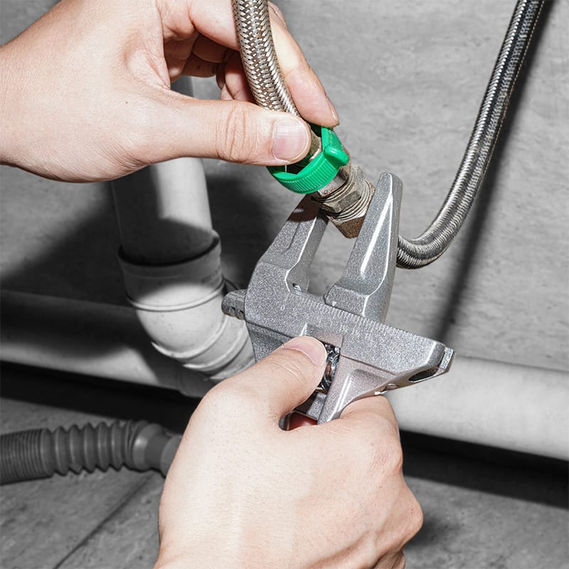 Close-up of Hands using a Tolsen lightweight adjustable wrench on plumbing fittings