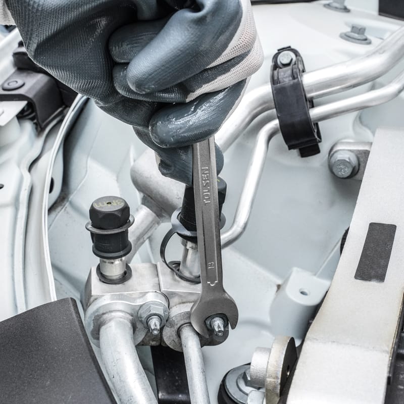 Close-up of gloved hand using a Tolsen 13mm combination spanner from the 5pcs set on automotive equipment