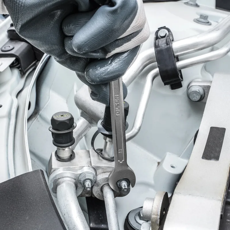Mechanic using a TOLSEN combination wrench for automotive engine repair in a tight space