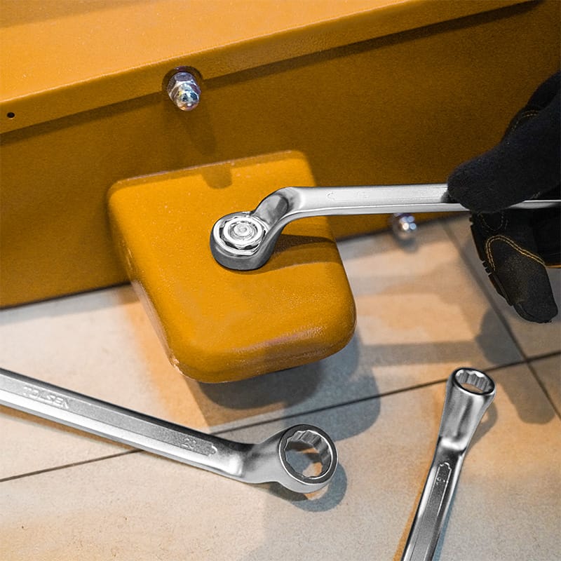 Mechanic using a TOLSEN double ring wrench to tighten a nut on heavy yellow industrial equipment