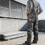 Full body rear view of a construction worker wearing Tolsen overalls at an industrial site.