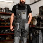 Mechanic standing in a workshop wearing Tolsen grey working overalls ready for heavy-duty tasks.