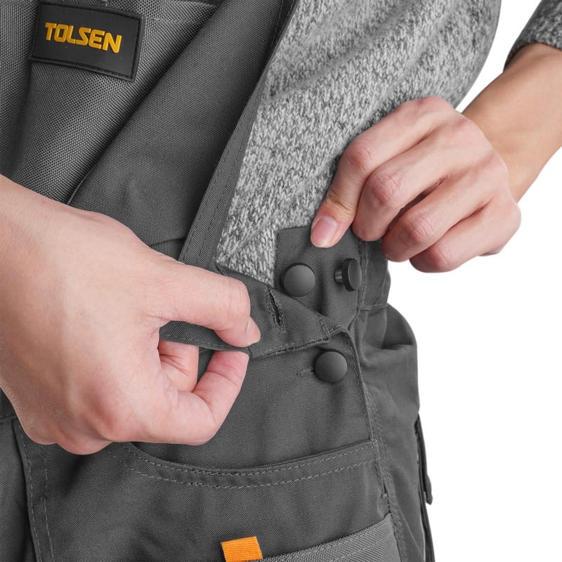 Model adjusting the side buttons on Tolsen working overalls for a comfortable and secure fit.