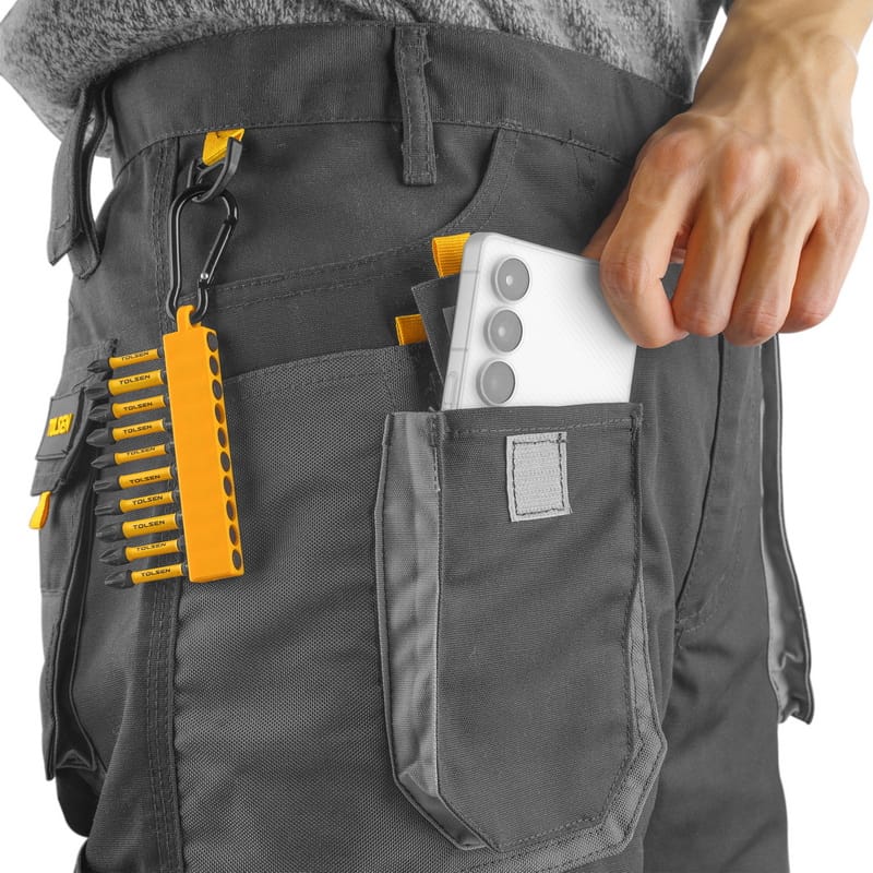 Close-up of Tolsen trouser pockets storing a smartphone and a screwdriver set, highlighting practical storage capacity.