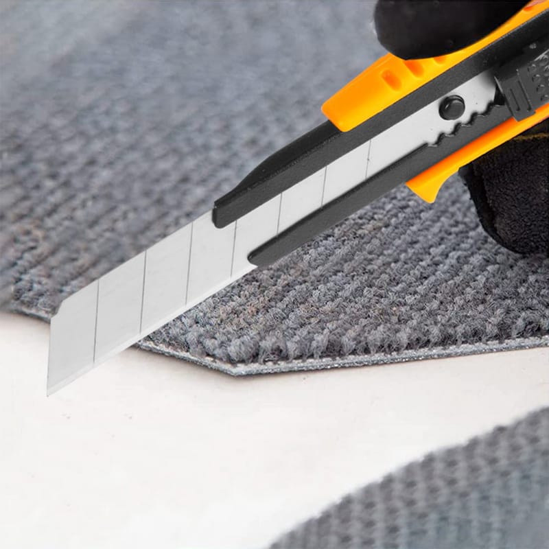 Tolsen snap-off blade utility knife cutting through grey carpet material with precision.