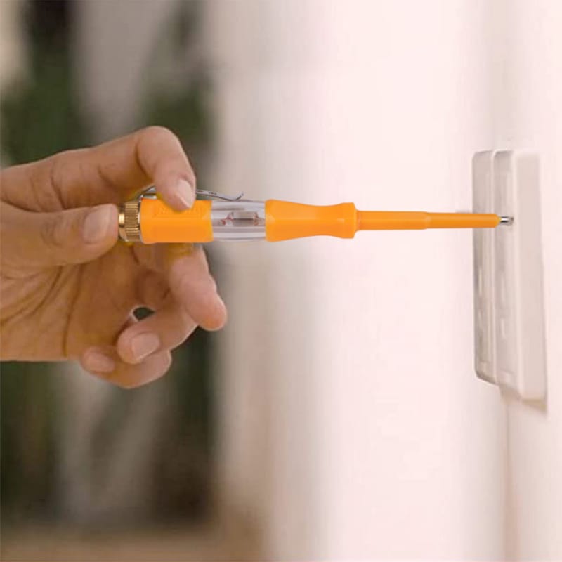 Hand holding a Tolsen voltage tester to check a standard wall power outlet for electricity.