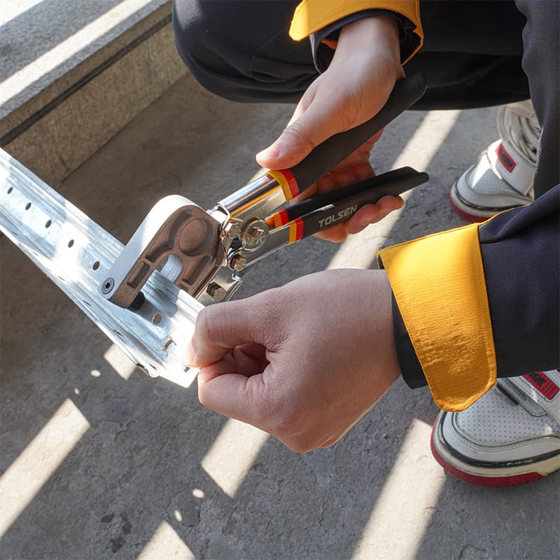 Close-up of using the Tolsen 11-inch Stud Crimper to fasten metal studs together
