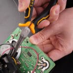 Close-up of hand using Tolsen 6 inch mini needle nose pliers to position a wire on a green circuit board