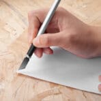 Hand using a Tolsen precision hobby knife to cut paper on a wooden surface