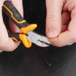 Tolsen diagonal cutting pliers cutting through a red electrical wire with precision.