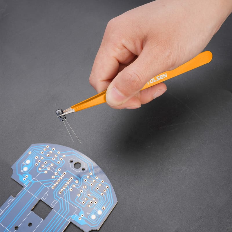 Using Tolsen straight tweezers to position a small capacitor onto a printed circuit board.