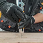 Close-up of a Tolsen multi-purpose putty knife functioning as a screwdriver on a wooden plank
