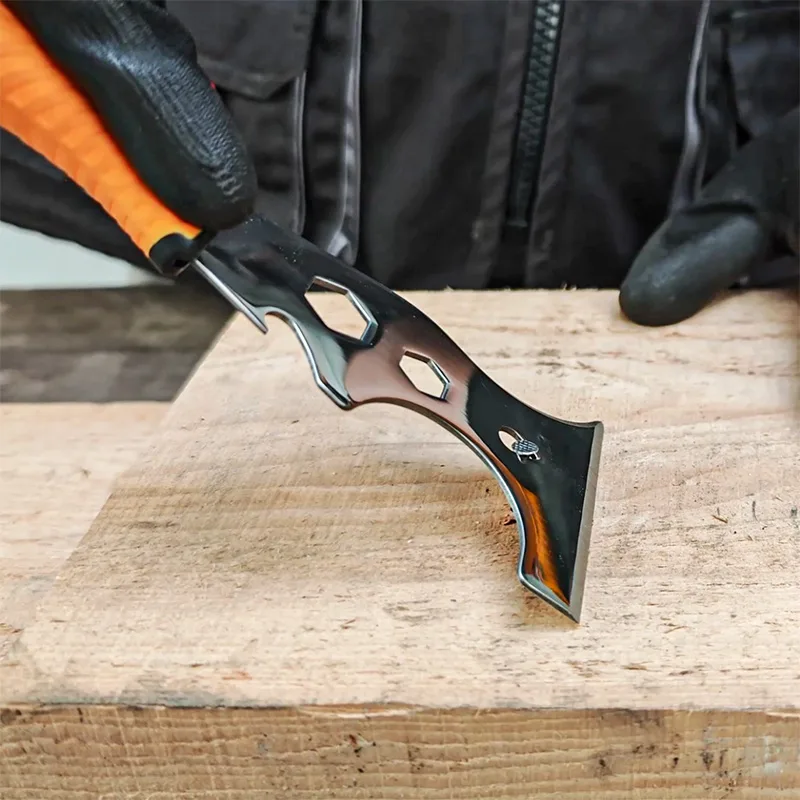 Close-up of a hand using a Tolsen 14-in-1 putty knife to remove nails from a board