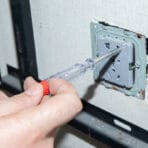 User checking for live electricity in a wall socket using the Tolsen voltage tester pen for safety.