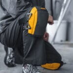 A construction worker kneeling on a concrete floor wearing TOLSEN heavy-duty knee pads, demonstrating comfortable knee protection during work.
